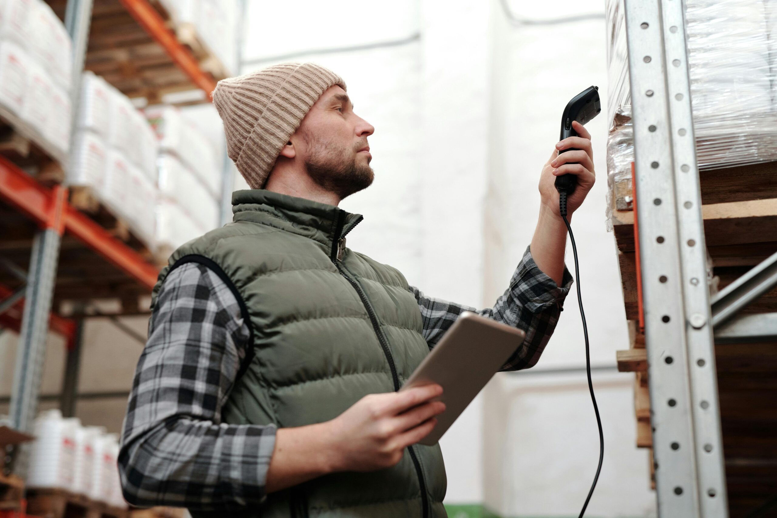pexels-photo-4483942-4483942 Male warehouse staff scanning inventory with handheld scanner and tablet indoors.
