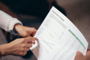Close-up of hands discussing a break-even analysis document in a business meeting.