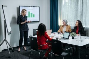A group of professional women engaged in a business presentation in a modern conference room.