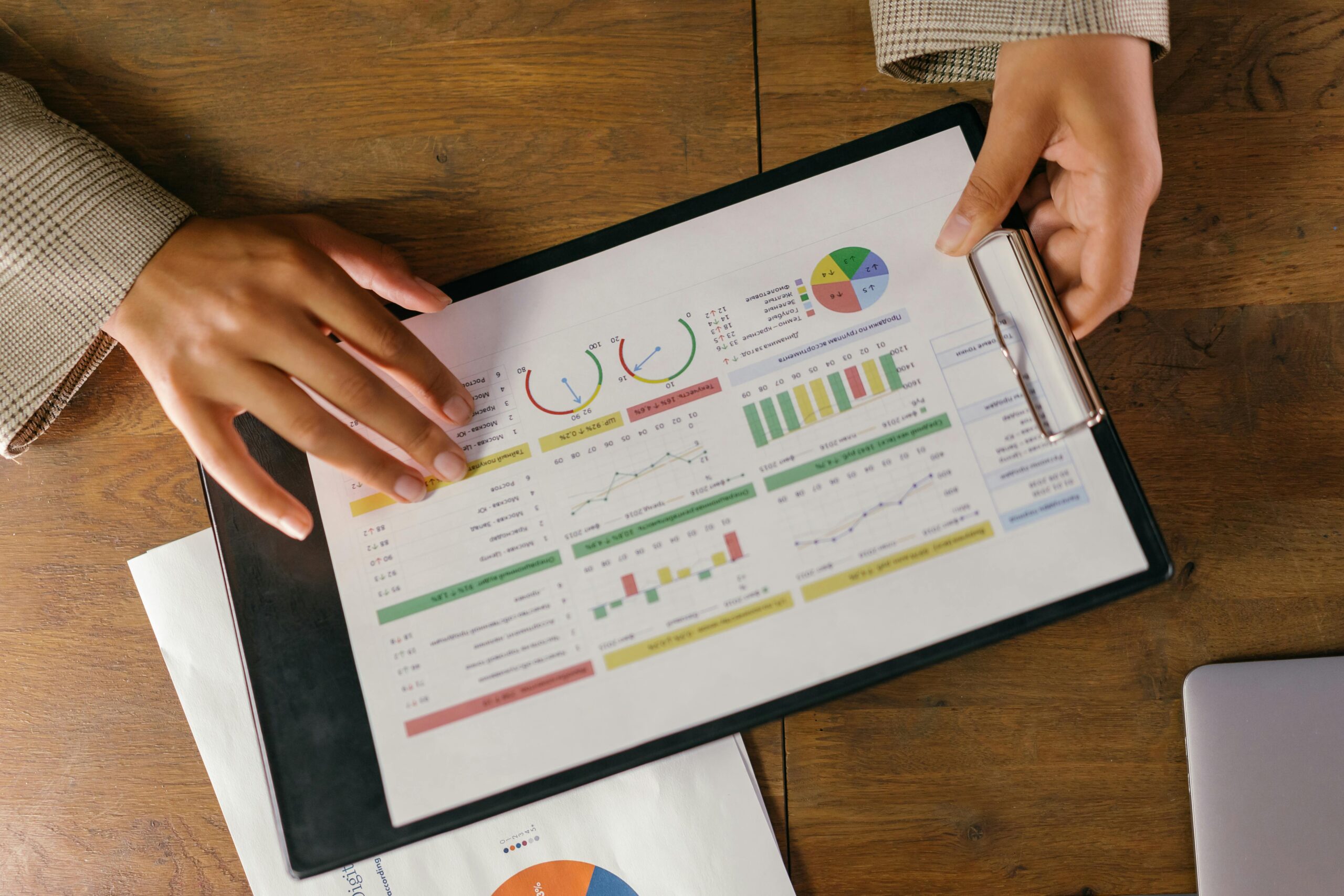 pexels-photo-9304917-9304917 Top view of hands holding a financial report with colorful graphs and charts, ideal for business presentations.